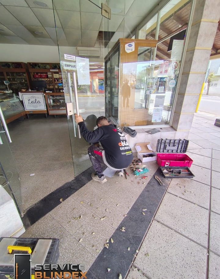 Técnico de Service Blindex reparando una puerta de vidrio en un comercio